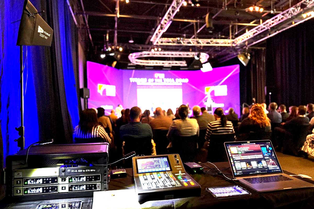 a professional AV technician's control station at a large conference or corporate event, with broadcast equipment and…