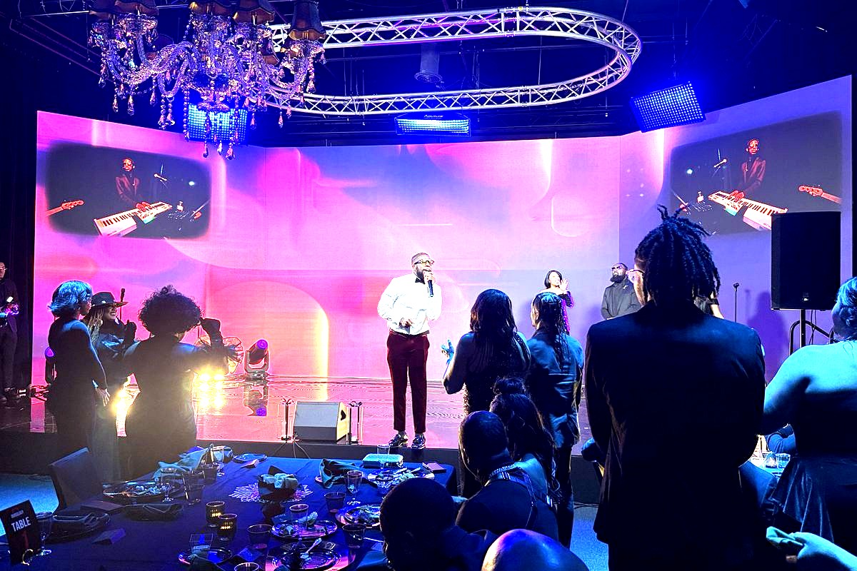 a lively indoor concert or performance event with a male performer in a white shirt and dark pants singing on stage…