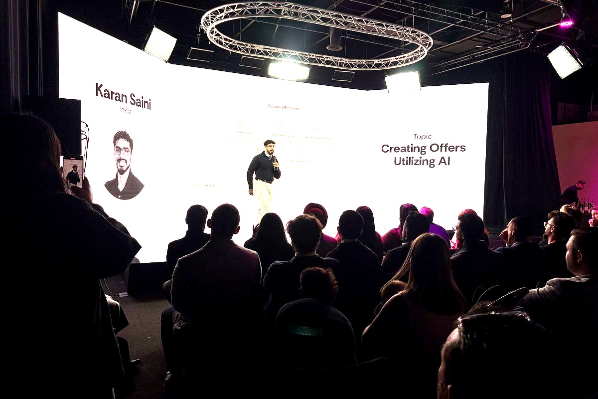 # Image Description

Karan Saini, a designer and creative strategist, presents on stage about 