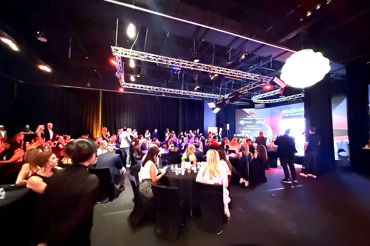 A large formal gala or awards event taking place in a professional venue with elegant black-tie attendees seated at round…
